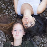 Twee beste vrienden die van het tienermeisje op de rotsen, hoogste mening liggen outdoors stock foto's Twee beste vrienden die van het tienermeisje op de rotsen, hoogste mening liggen outdoors stock foto's