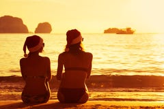 Twee dames in Kerstmiskappen bij zonsondergangstrand Stock Fotografie Twee dames in Kerstmiskappen bij zonsondergangstrand Stock Fotografie