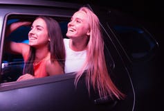 Twee gelukkige meisjes kijken buiten auto Zij kijken ongecompliceerd en glimlachen Het blondehaar golft Het is stock afbeeldingen Twee gelukkige meisjes kijken buiten auto Zij kijken ongecompliceerd en glimlachen Het blondehaar golft Het is stock afbeeldingen