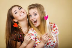 Twee gelukkige vrouwen die hart op stok houden royalty-vrije stock fotografie Twee gelukkige vrouwen die hart op stok houden royalty-vrije stock fotografie