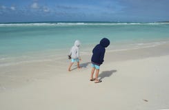 Twee jongens die in hoodies op wit zand van een tropisch strand lopen stock foto Twee jongens die in hoodies op wit zand van een tropisch strand lopen stock foto