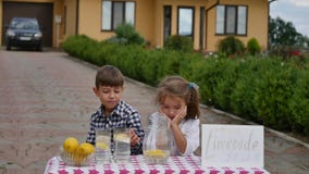Twee kleine jonge geitjes verkopen limonade bij een eigengemaakte limonadetribune op een zonnige dag met een prijsteken voor een Stock Afbeeldingen Twee kleine jonge geitjes verkopen limonade bij een eigengemaakte limonadetribune op een zonnige dag met een prijsteken voor een Stock Afbeeldingen