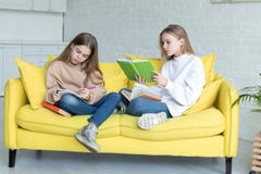 Twee kleine zusters die in vrijetijdskleding samen op gele bank zitten royalty-vrije stock afbeelding Twee kleine zusters die in vrijetijdskleding samen op gele bank zitten royalty-vrije stock afbeelding