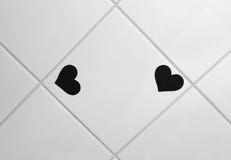 Twee kleine zwarte hart gevormde stickers op verglaasde tegel stock afbeeldingen Twee kleine zwarte hart gevormde stickers op verglaasde tegel stock afbeeldingen