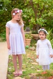 Twee meisjes in witte kleding en bloemkroon die pret hebben een de zomertuin royalty-vrije stock fotografie Twee meisjes in witte kleding en bloemkroon die pret hebben een de zomertuin royalty-vrije stock fotografie
