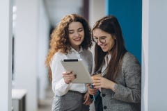 Twee vrouwelijke leidende directeuren die ideeën van project op digitale tablet bespreken terwijl het lopen neer in bureauzaal, stock foto Twee vrouwelijke leidende directeuren die ideeën van project op digitale tablet bespreken terwijl het lopen neer in bureauzaal, stock foto