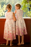 Twin girls in summer dresses. On porch laughing stock photos Twin girls in summer dresses. On porch laughing stock photos