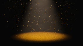 Twinkling golden glitter falling through a cone of light on a stage