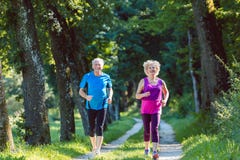 Two active seniors with a healthy lifestyle smiling while jogging Stock Photo Two active seniors with a healthy lifestyle smiling while jogging Stock Photo