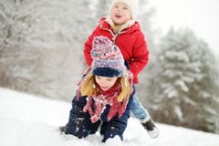 Two adorable little girls having fun together in beautiful winter park. Beautiful sisters playing in a snow. royalty free stock photo Two adorable little girls having fun together in beautiful winter park. Beautiful sisters playing in a snow. royalty free stock photo