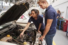 Two apprentice mechanics looking at the engine in a car royalty free stock photo Two apprentice mechanics looking at the engine in a car royalty free stock photo