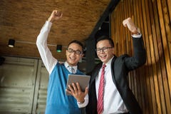 Two Asian businessman stand and looking at tablet, they cheerful and celebrated his successful in mission. royalty free stock photos Two Asian businessman stand and looking at tablet, they cheerful and celebrated his successful in mission. royalty free stock photos
