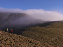 Two asian men standing on the hill of mountains, and there is a thick fog drifting torward where they are royalty free stock photos Two asian men standing on the hill of mountains, and there is a thick fog drifting torward where they are royalty free stock photos
