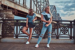 Two beautiful hipster girls standing with skateboard against a bridge. stock photography Two beautiful hipster girls standing with skateboard against a bridge. stock photography