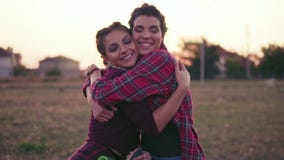 Two best friends hugging each other and looking in the camera smiling. Happy young woman cuddle and hug showing love and