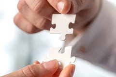 Two businesspeople fitting together puzzle pieces Stock Photo Two businesspeople fitting together puzzle pieces Stock Photo