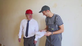 Two cheerful builders are discussing the construction plan and laughing. Senior engineer and young worker discuss the stock video Two cheerful builders are discussing the construction plan and laughing. Senior engineer and young worker discuss the stock video