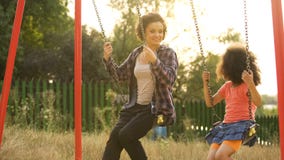 Two cheerful sisters swinging together at outdoor child playground, happiness royalty free stock image Two cheerful sisters swinging together at outdoor child playground, happiness royalty free stock image