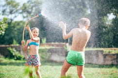 Two childs, brother and sister, have fun, when play with watering hose in summer garden stock photography Two childs, brother and sister, have fun, when play with watering hose in summer garden stock photography