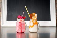 Two crazy milkshakes, with a blank blackboard royalty free stock images Two crazy milkshakes, with a blank blackboard royalty free stock images
