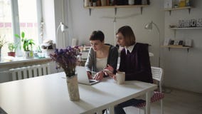 Two creative woman at table and using notebook for shopping online stock video Two creative woman at table and using notebook for shopping online stock video