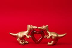 Two  cute golden dinosaurs with red heart on a red background. Creative minimal greeting card on Valentines day. Love concept