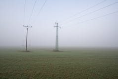 Two electric poles on the field in fog stock photos Two electric poles on the field in fog stock photos