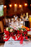 Two empty wedding glasses, decorated with greenery, red roses and ribbon, standing on the banquet table. royalty free stock photo Two empty wedding glasses, decorated with greenery, red roses and ribbon, standing on the banquet table. royalty free stock photo