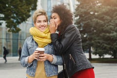 Two female friends sharing secrets outdoors stock photo Two female friends sharing secrets outdoors stock photo