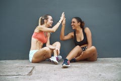 Laughing friends high fiving during a break from their workout