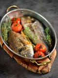 Two Freshly Baked Dorado Fish With Thyme, Cherry Tomatoes, Red Onion And Lemon In A Copper Frying Pan. Stock Images