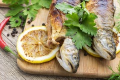 Two fried fish of kind of salmon with aromatic herbs and lemon Stock Photos Two fried fish of kind of salmon with aromatic herbs and lemon Stock Photos