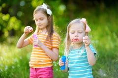 Two funny little sisters blowing soap bubbles outdoors royalty free stock image Two funny little sisters blowing soap bubbles outdoors royalty free stock image