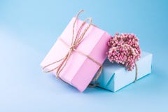 Two gift boxes of pink and blue with bows of twine decorated with small pink flowers on a blue background. stock image Two gift boxes of pink and blue with bows of twine decorated with small pink flowers on a blue background. stock image
