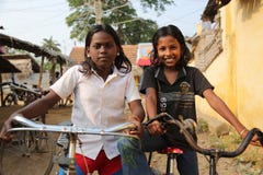 Two girls are sitting on their bicycles and posing
