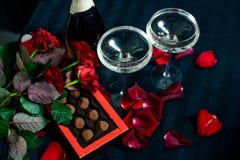 Two glasses of champagne, red roses, petals and chocolates on a black background royalty free stock photo Two glasses of champagne, red roses, petals and chocolates on a black background royalty free stock photo