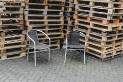 Two wicker chairs placed in front of stacks of pallets stock images Two wicker chairs placed in front of stacks of pallets stock images