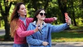 Two happy girls friends make selfie on the mobile phone on the city park stock video Two happy girls friends make selfie on the mobile phone on the city park stock video