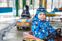Two happy sibling boys in blue jackets and rain boots playing with big old toy car, outdoors. Kids leisure on cold day in winter, royalty free stock images Two happy sibling boys in blue jackets and rain boots playing with big old toy car, outdoors. Kids leisure on cold day in winter, royalty free stock images