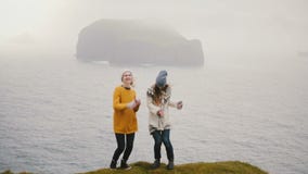Two happy traveling woman dancing a crazy dance on the shore of a sea. Cheerful female having fun on nature. stock video footage Two happy traveling woman dancing a crazy dance on the shore of a sea. Cheerful female having fun on nature. stock video footage
