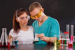 Two lab technicians are examining a flask with a green liquid that the guy is holding in his hand. royalty free stock photography Two lab technicians are examining a flask with a green liquid that the guy is holding in his hand. royalty free stock photography