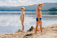 Two little boys in caps are on the lake in the summer stock images Two little boys in caps are on the lake in the summer stock images
