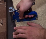 Two man hands using stapler upholstering paricle board with leatherette stock photo Two man hands using stapler upholstering paricle board with leatherette stock photo