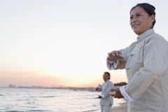 Two Older People Practicing Taijiquan On The Beach At Sunset, China Stock Photo Two Older People Practicing Taijiquan On The Beach At Sunset, China Stock Photo