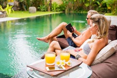 Two persons using tech gadgets by the pool Stock Photos Two persons using tech gadgets by the pool Stock Photos
