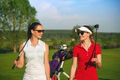 Two pretty women golfers walking at golf course