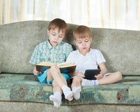 Two reading boys. With paper and electronic book Royalty Free Stock Images Two reading boys. With paper and electronic book Royalty Free Stock Images
