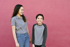 Two Sibling Children Stand Against a Pink Wall Laughing and Having Fun royalty free stock photo Two Sibling Children Stand Against a Pink Wall Laughing and Having Fun royalty free stock photo