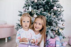 Two sisters at home with Christmas tree and presents. Happy children girls with Christmas gift boxes and decorations. Royalty Free Stock Images Two sisters at home with Christmas tree and presents. Happy children girls with Christmas gift boxes and decorations. Royalty Free Stock Images