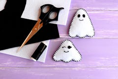 Two small white ghosts crafts, felt sheets, scissors, thread, needle on lilac wooden background. Hand Halloween decor idea Stock Image Two small white ghosts crafts, felt sheets, scissors, thread, needle on lilac wooden background. Hand Halloween decor idea Stock Image